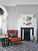 Cognac-colored leather chair and side table in front of the fireplace in the living room with a light gray wall