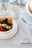 Bowl of berries and cape gooseberries on table with linen tablecloth