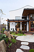 Blick vom Garten mit Natursteinplatten auf elegante Terrasse