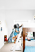 Bunk bed in white children's room, boy on bed ladder