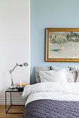Wintry landscape painting on blue wall above bed