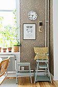 Blue-grey high chair and stool against vintage wallpaper