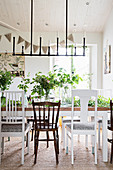 Simple candle chandelier above dining table and various chairs