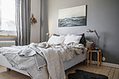 Seascape in bedroom on blue-grey wall above bed