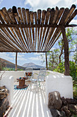 Weiß gestrichene Terrasse mit rustikaler Sonnenschutz