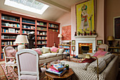 Library, antique armchairs and sofa in front of fireplace in living room in shades of pink