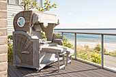 Wicker beach chair on wooden terrace with sea view