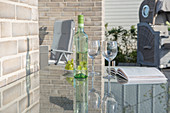 Glass table on terrace of house clad in pale brick