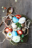 Coloured Easter eggs in a wooden bowl and wooden cutlery