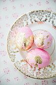 Rosafarbene Eier mit Blattgold auf nostalgischem Teller