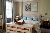 Chest of drawers at foot of bed with headboard and matching bedspread