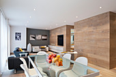 Oak panelling, glass dining table and designer chairs in modern interior