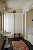 Wood panelled bathroom with African rug and stool