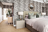 Elegant double bed with bedside cabinets in bedroom with patterned wallpaper