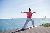 Woman doing yoga on terrace by the sea