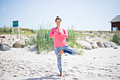 Frau macht Yoga-Übung am Strand
