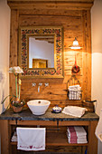 Washstand with mirror on wooden wall in farmhouse