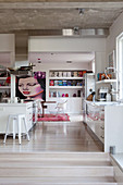 White kitchen, built-in shelves and artwork in an open living room with concrete ceiling