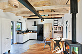 Open-plan interior of converted barn with log-burning stove and wooden ceiling