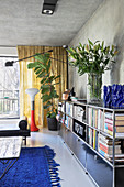 Vase of lilies on book shelves in living room with concrete ceiling