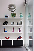 Vase collection on white wall shelves above the sideboard