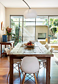 Modern shell chairs on a rustic wooden table in front of the window front