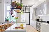 Suspended shelf above island counter in bright, open-plan kitchen
