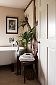 Antique chair next to free-standing bathtub with modern tap fitting against half-timbered wall