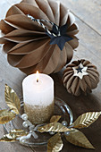 Original arrangement of handcrafted honeycomb balls and golden leaves around candle