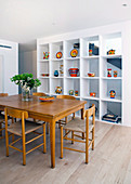 Dining table with chairs in front of white, floor-to-ceiling shelf in the dining room