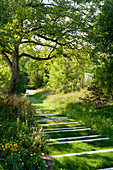 Grass pathway leading through summery gardens in Périgord Vert (France)
