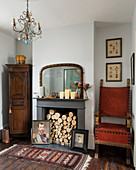 Firewood stacked in open fireplace surrounded by antique furniture