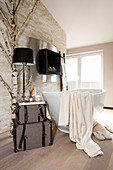 Free-standing bathtub in front of fireplace in stone wall