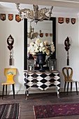 Bombe chest painted with black-and-white diamond pattern flanked by designer chairs