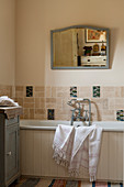 Pale wall tiles and mirror on wall above bath in bathroom