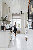 Woman in bright kitchen with white wooden floor