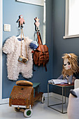 Coat pegs and ride-on car in nursery with blue-grey walls