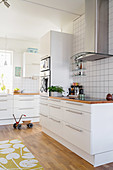 Helle, großzügige Küche in Weiß mit Holzboden