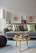 Round coffee table in front of grey sofa with graphic patterns on scatter cushions