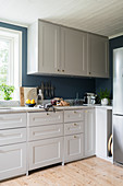White cupboards in kitchen with petrol-blue walls