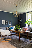 Grey sofas and classic rocking chair around coffee table in living room with grey-blue walls