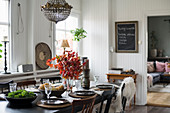 Dining table set for autumn dinner in interior with white wood-panelled walls