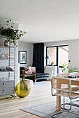 Übereck-Wohnraum mit schwarzem Samtsofa und hellem Esstisch mit Freischwingerstühlen