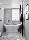 Freestanding bathtub in small, elegant gray bathroom