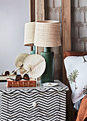 Black and white bedside tables next to bed with palm-themed bed linen