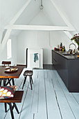 Black kitchen counter, dining table and seating in open-plan attic interior