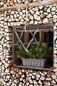 Star made of branches covered in lichen in front of window surrounded with stacked firewood