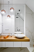 Washstand with countertop sink in elegant bathroom with marble wall