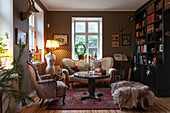 Antique sofa, elegantly patterned wallpaper and bookcase in living room