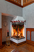 Lit candles in open fireplace with festive decorations
